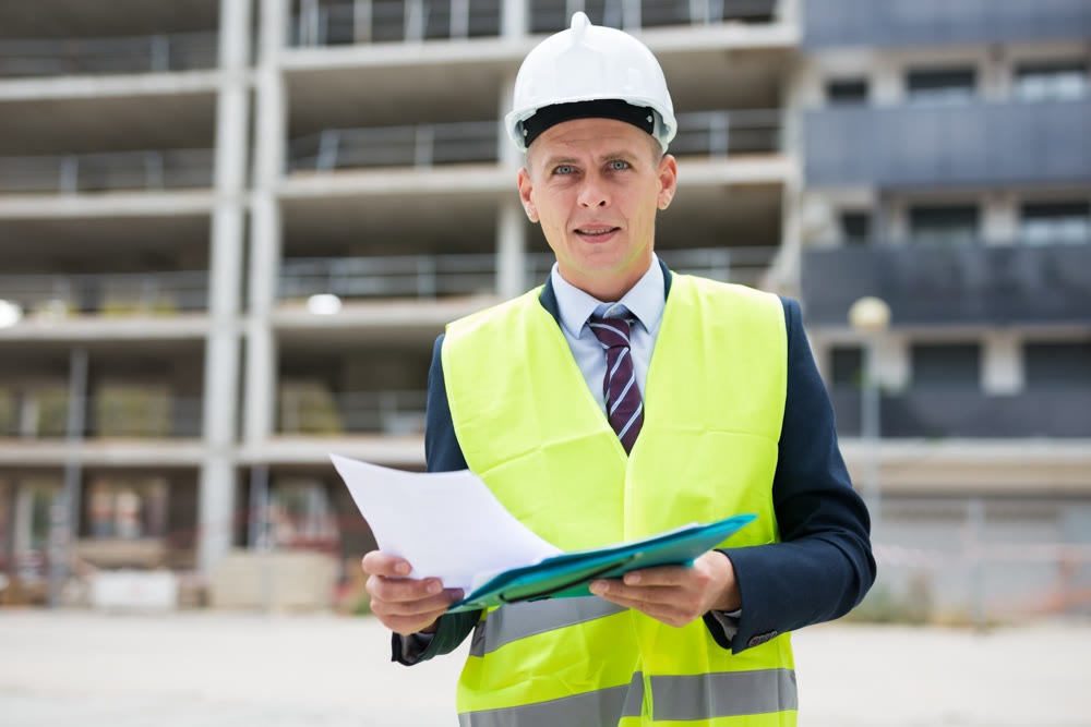 Architect standing on building site with documentation