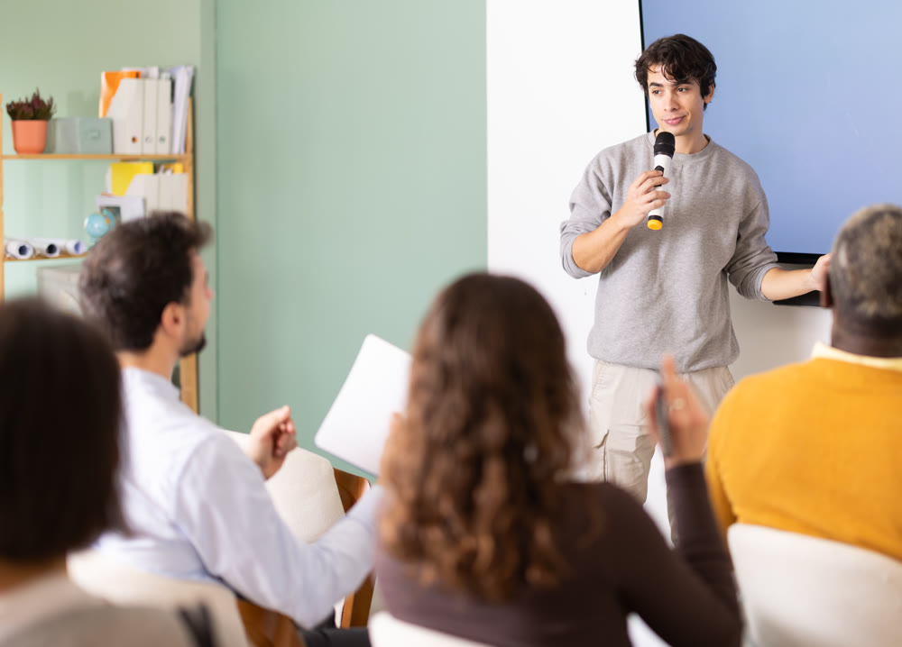 Young man teacher gives lecture to group in lecture hall