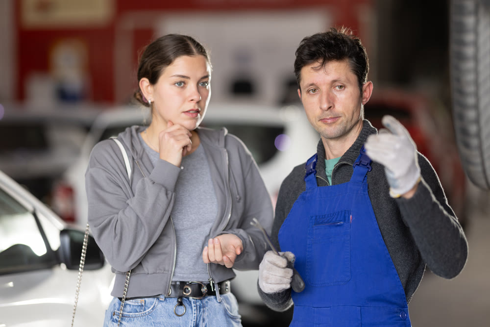 Male auto mechanic discussing with woman the cost and time to repair her car at car service
