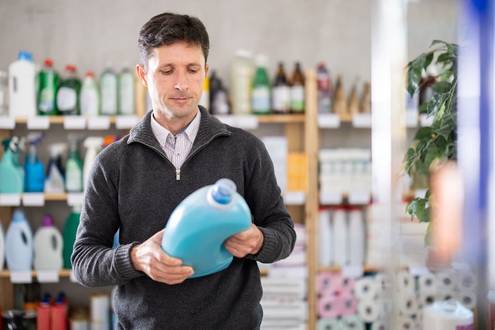 Man consumer with household chemical products for washing indoors