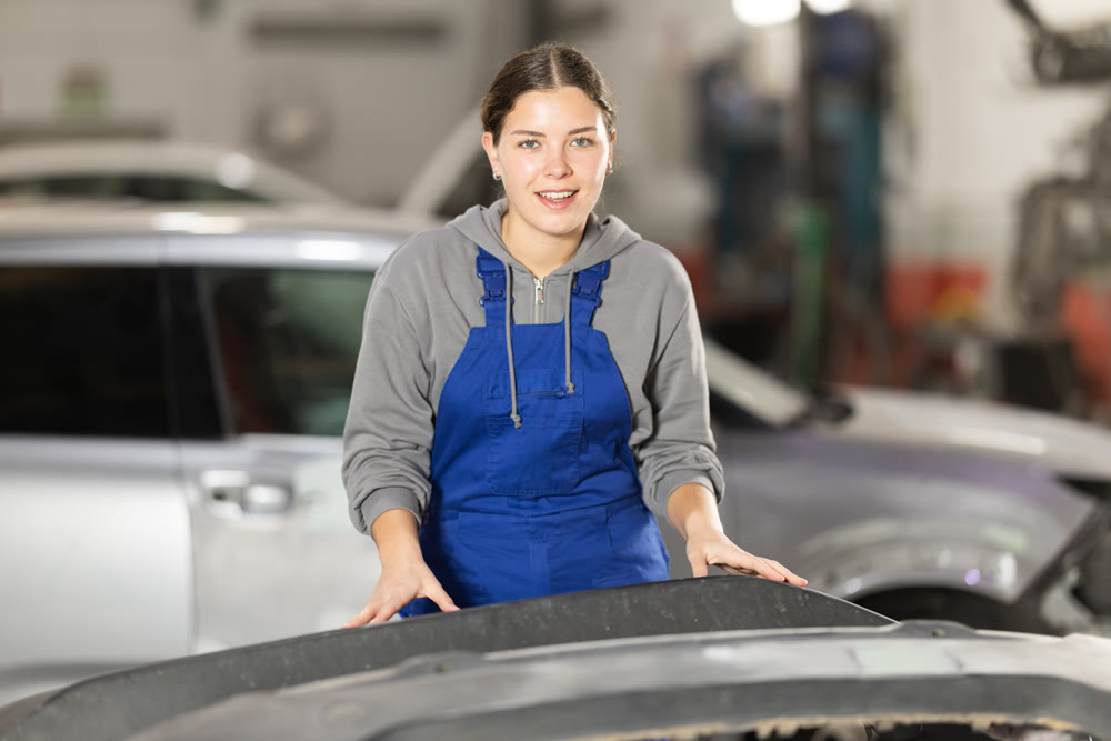 Portrait of a positive girl auto mechanic in the interior of car service