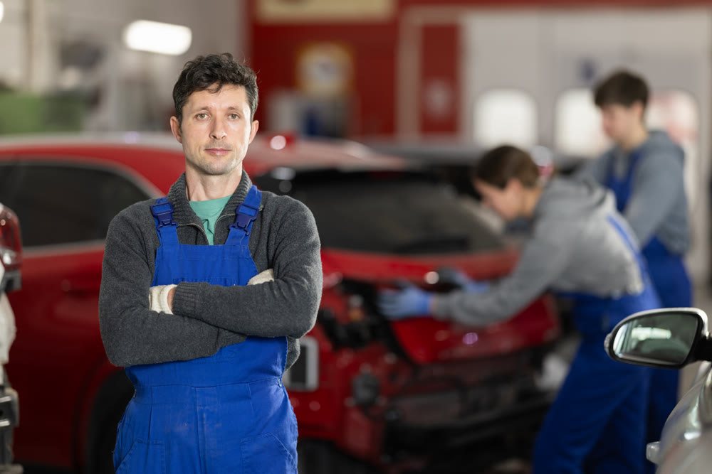 Portrait of a positive girl auto mechanic in the interior of car service
