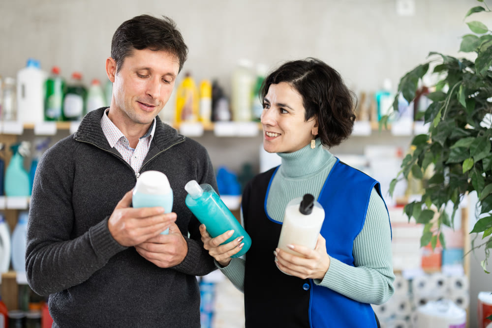 Female saleswoman offers man buy shampoo or shower gel in supermarket