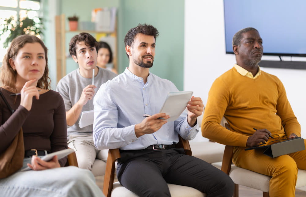 Young man listens and takes notes in lecture hall