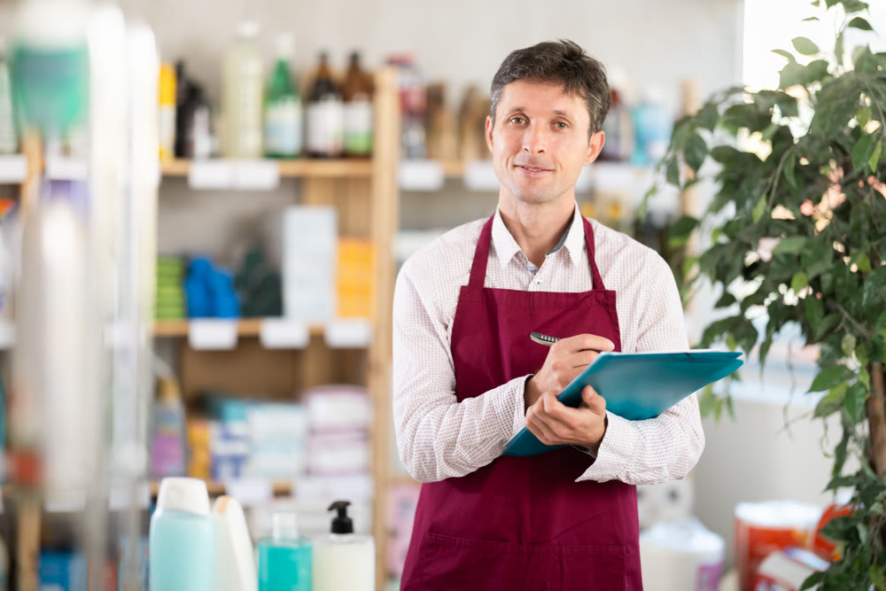 Middle-aged marketer taking record of inventory in household store