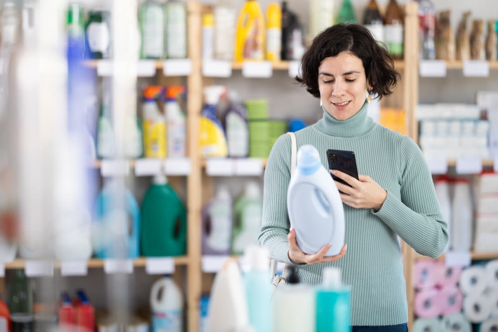 Middle-aged woman scanning QR-code on detergent at supermarket
