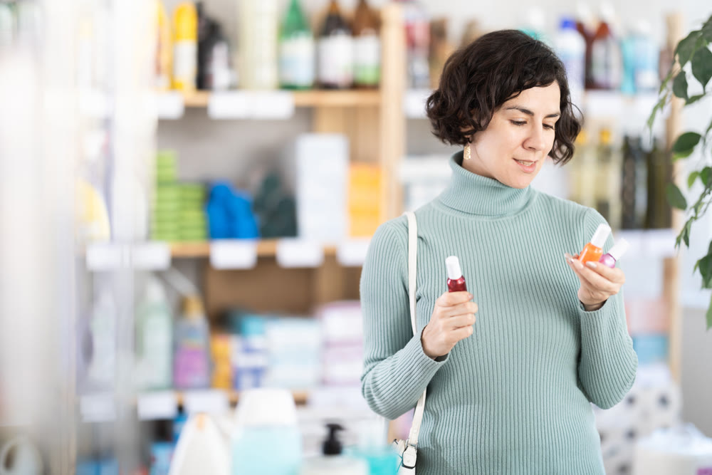 Middle-aged woman choosing lipsticks in retail store