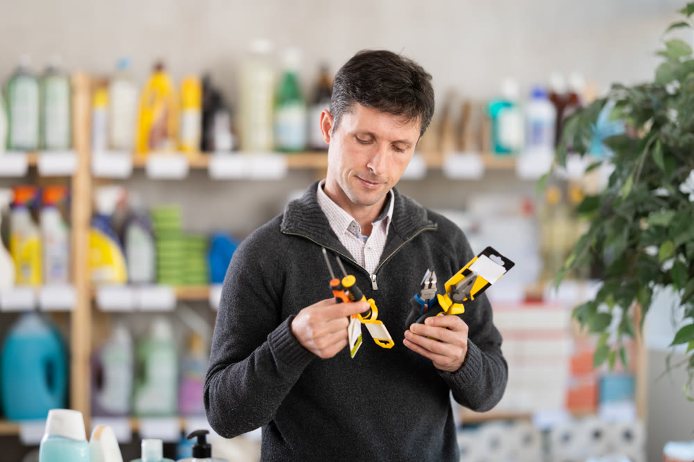 Male client in store inspects set of hand tools. Buyer selects necessary items for minor repairs