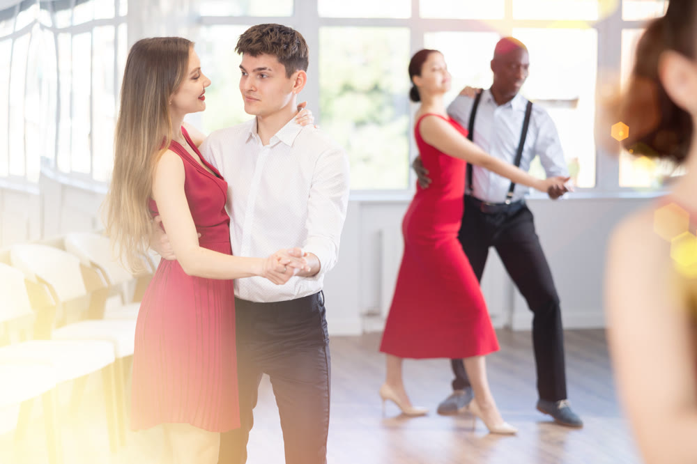 Group of multinational sports people rehearsing social dance in dance hall
