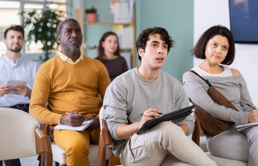 Young man listening to lecture and taking notes on tablet