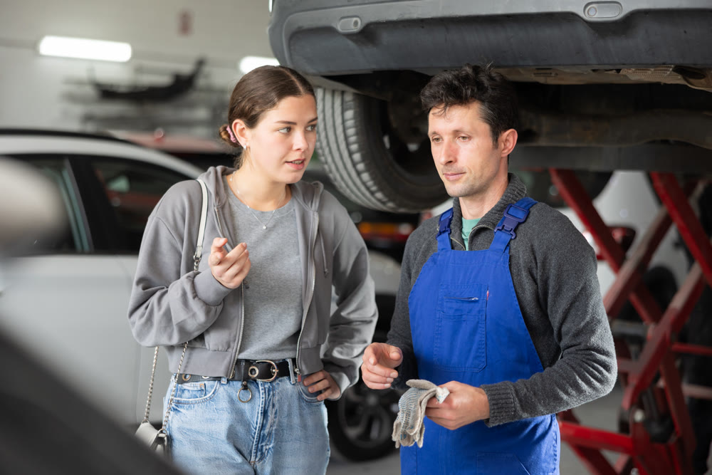 Male auto mechanic discussing with woman the cost and time to repair her car at car service