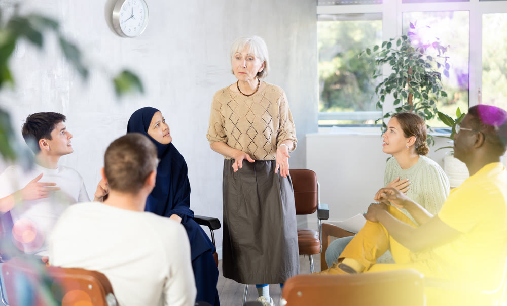 Mature female teacher giving lecture to group of multinational students