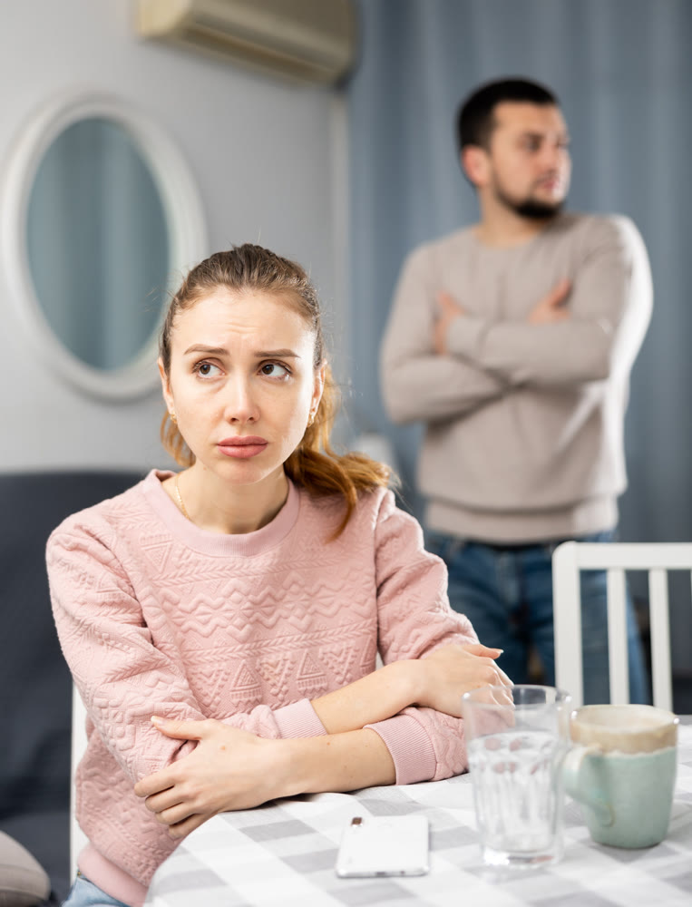 Woman sitting at table during quarrel with her husband