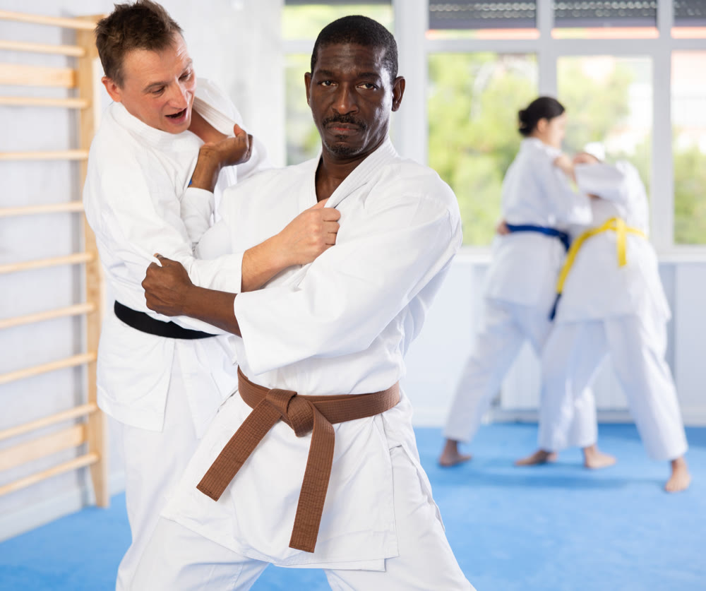 Middle-aged male judo practitioner engaged in wrestling in sports hall