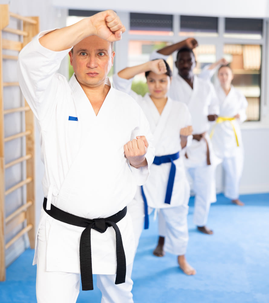Women and men in kimono in fight stance during group karate training