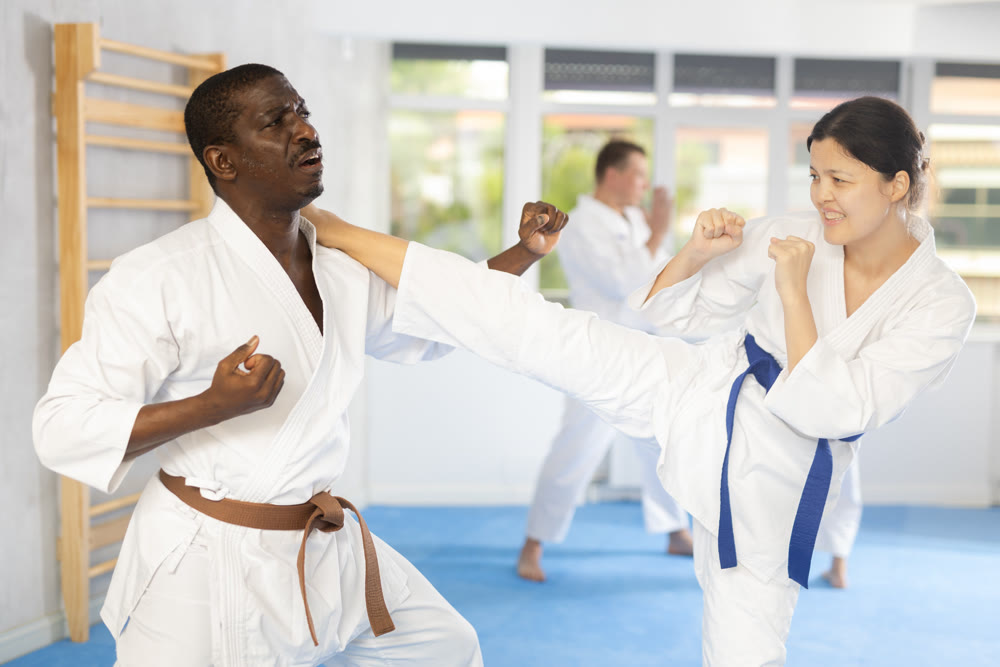 Adult man and young woman training judo techniques