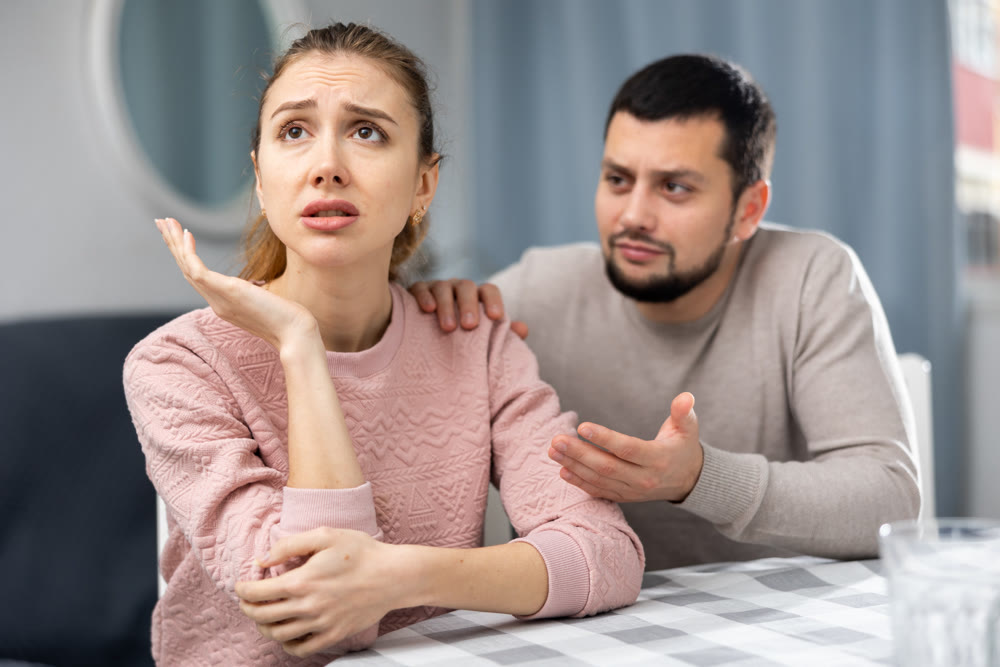 Apologetic husband calming upset wife after spat at home