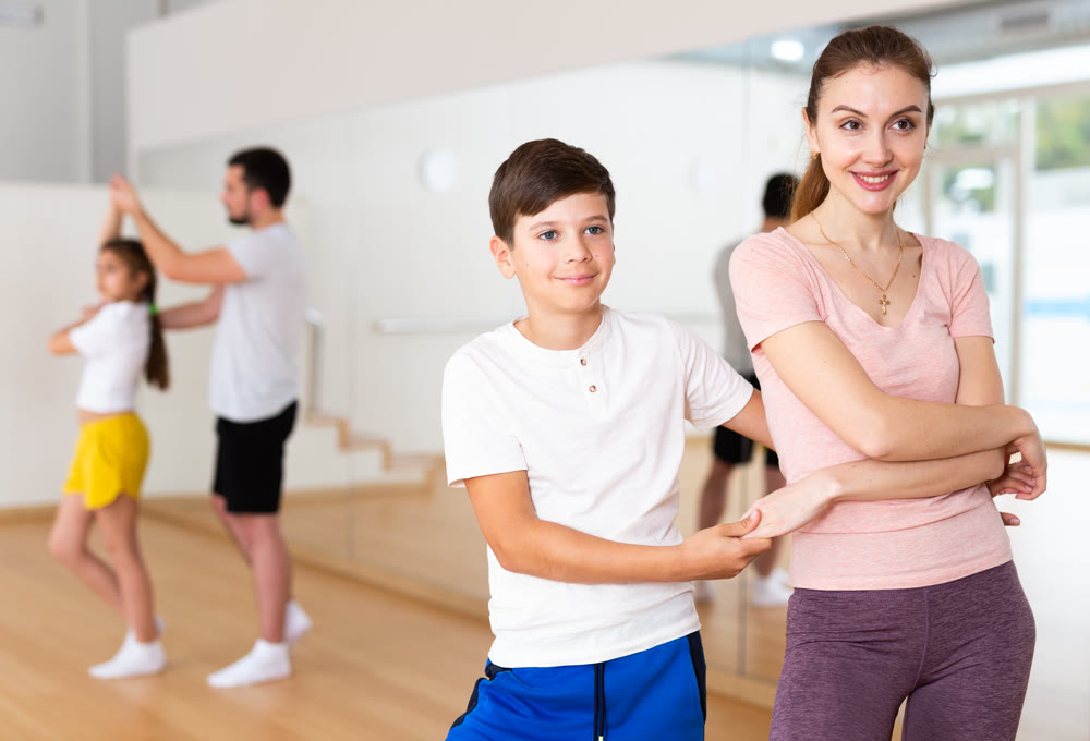 Tween boy enjoying active dance in pair with mother