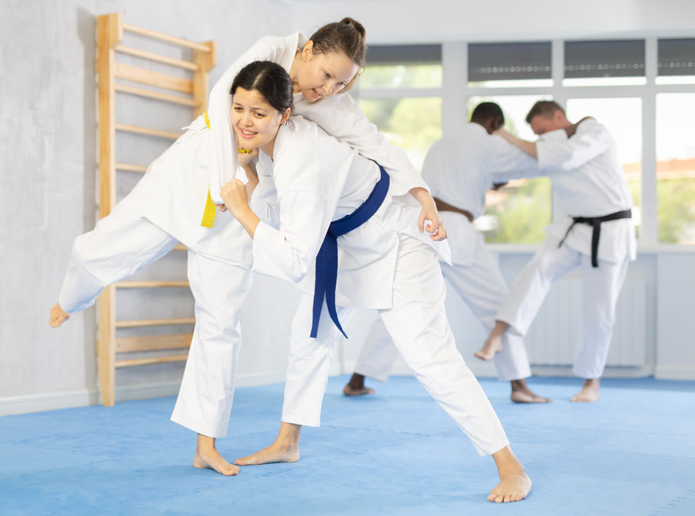 Girl tapping woman out with jiu jitsu grappling submission in gym
