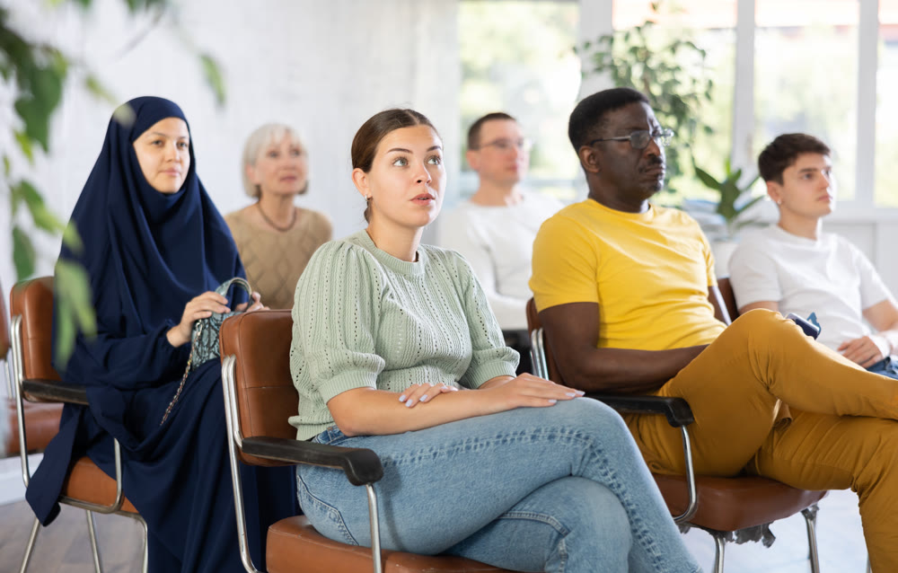 Young girl sitting at lecture with group of women and men