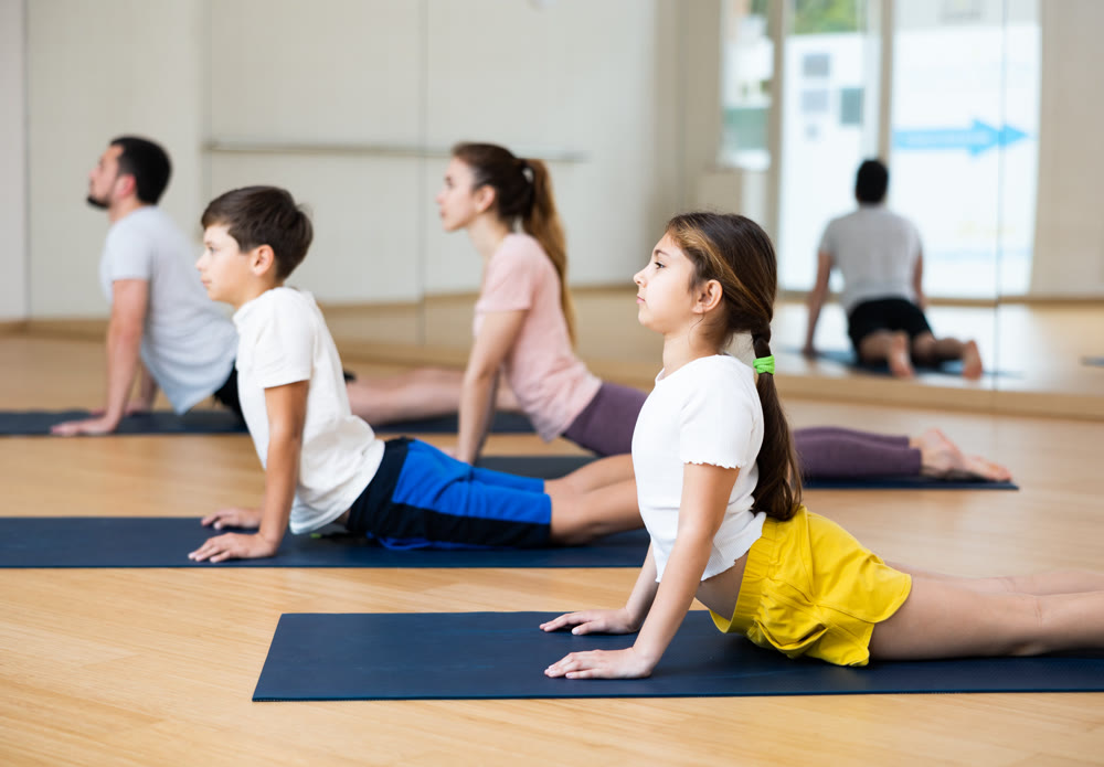 Family of four practicing yoga at gym