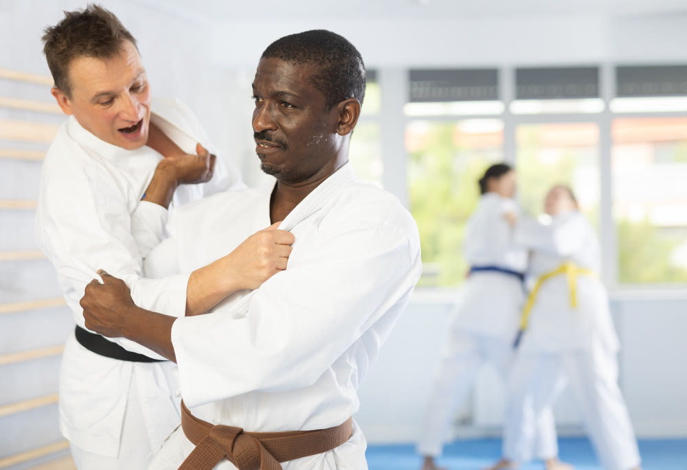 Middle-aged male judo practitioner engaged in wrestling in sports hall