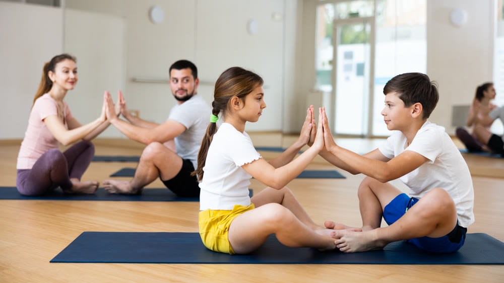 Siblings practicing partner yoga poses at gym