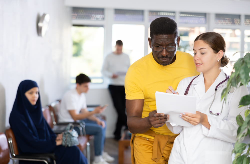 Young female medic gives document to african man for signing