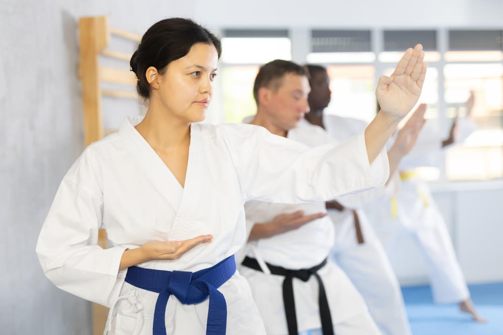 Multinational students repeat position and perform sequence of punches and painful techniques kata