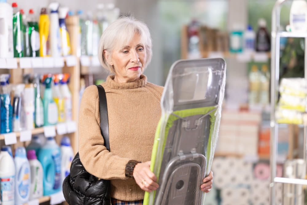 Elderly woman buys convenient lightweight ironing board at hardware store