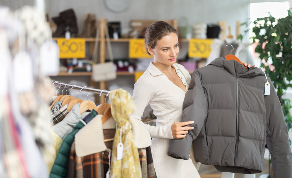 Young woman chooses sweater in clothing store