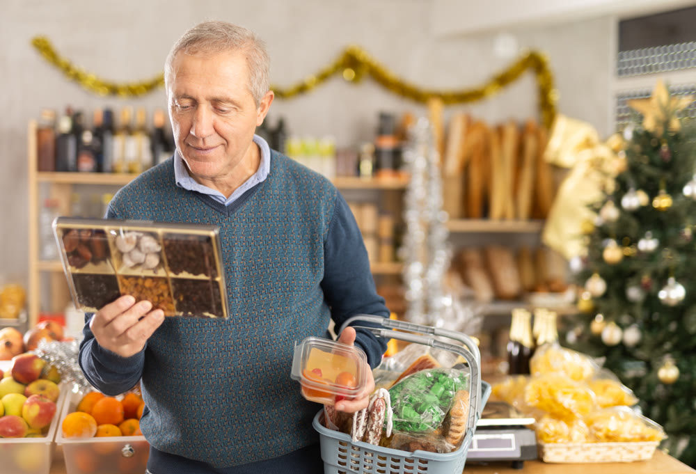 Elderly man chooses dried fruits and fruit jelly at grocery store