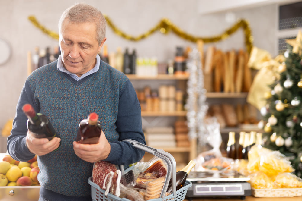 Elderly man choosing whiskey in grocery store