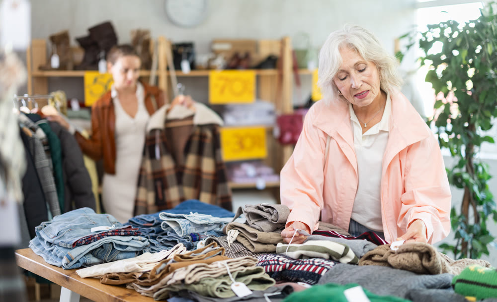 Elderly woman choosing sweaters against the background of female buyer