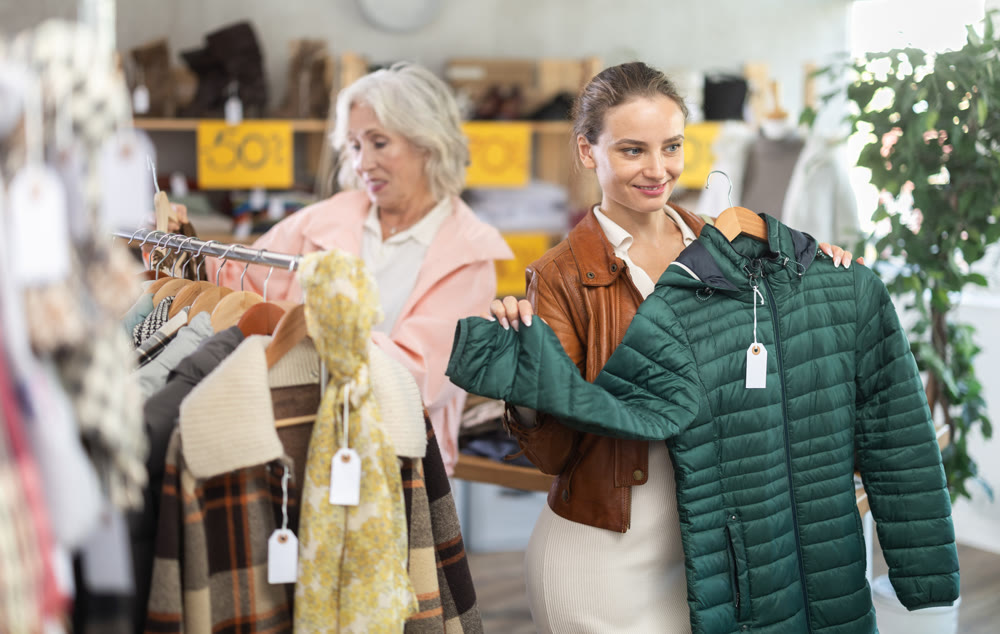 woman, together with a mature woman, chooses outerwear