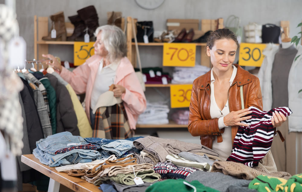 Adult woman choosing sweaters against the background of pensioner buyer