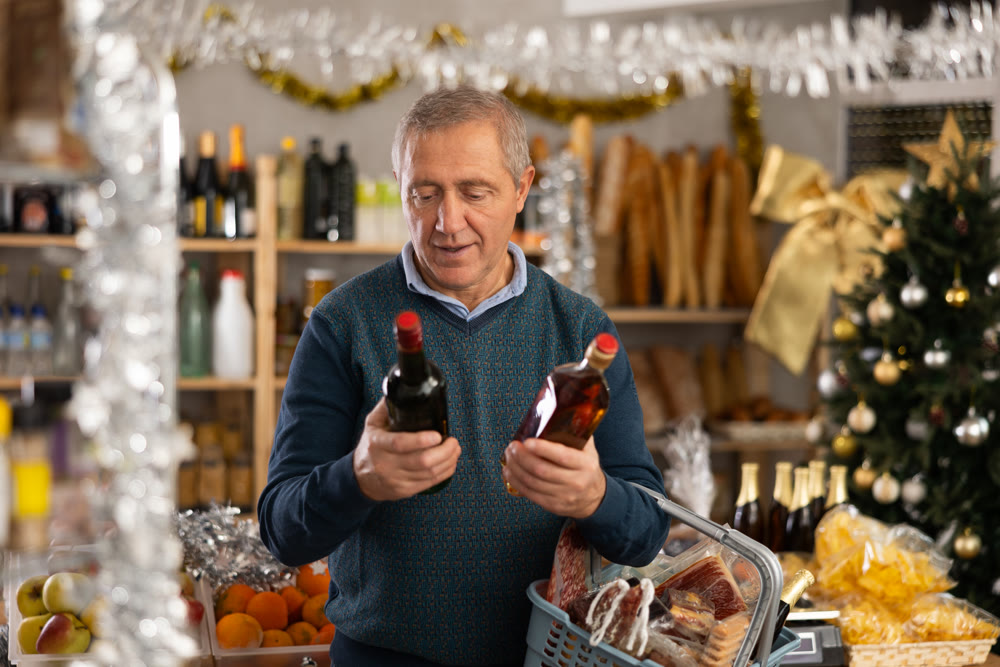Elderly man choosing whiskey in grocery store