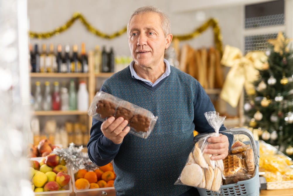 Retired man chooses cookies for a holiday table in supermarket