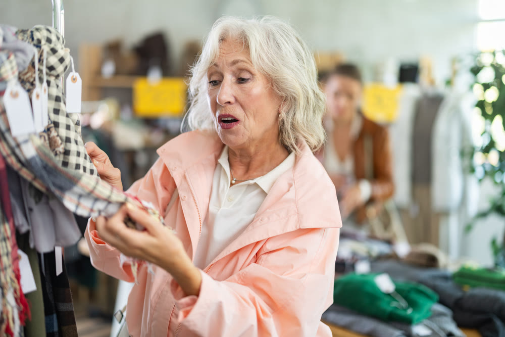 Elderly woman chooses scarf in clothing store
