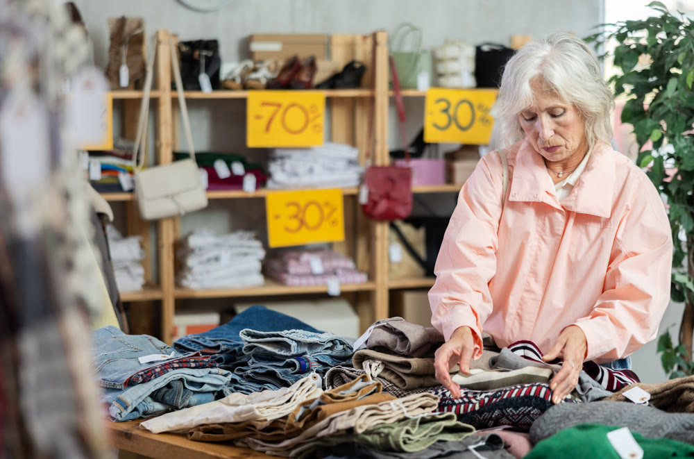 Elderly woman choosing down sweater in clothing store