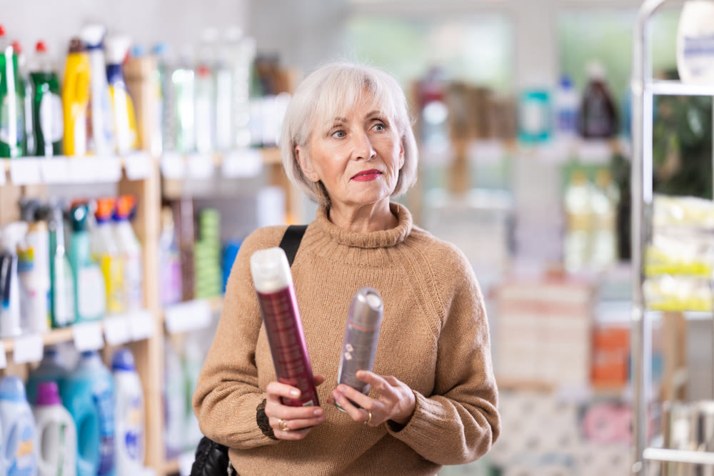 Choosing hairspray in supermarket - mature woman making choice