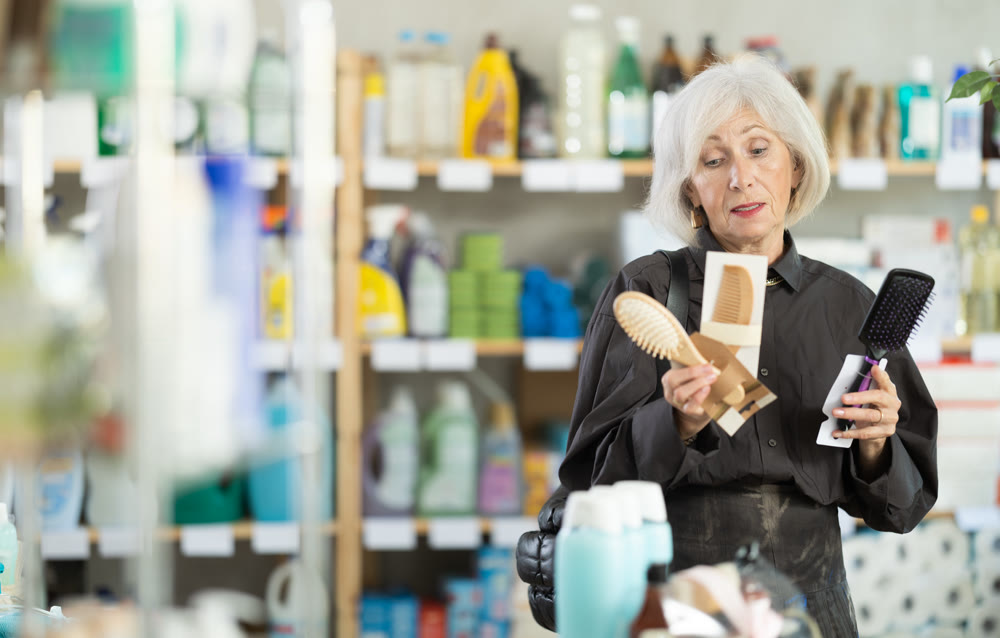 Female shopper chooses best comb in household supermarket