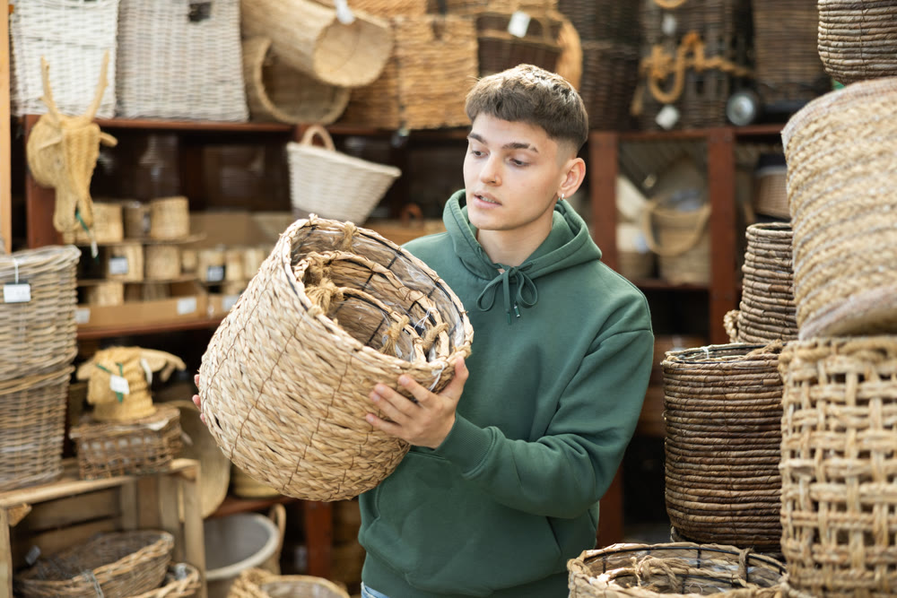 Male shopper in furniture center chooses new wicker laundry basket