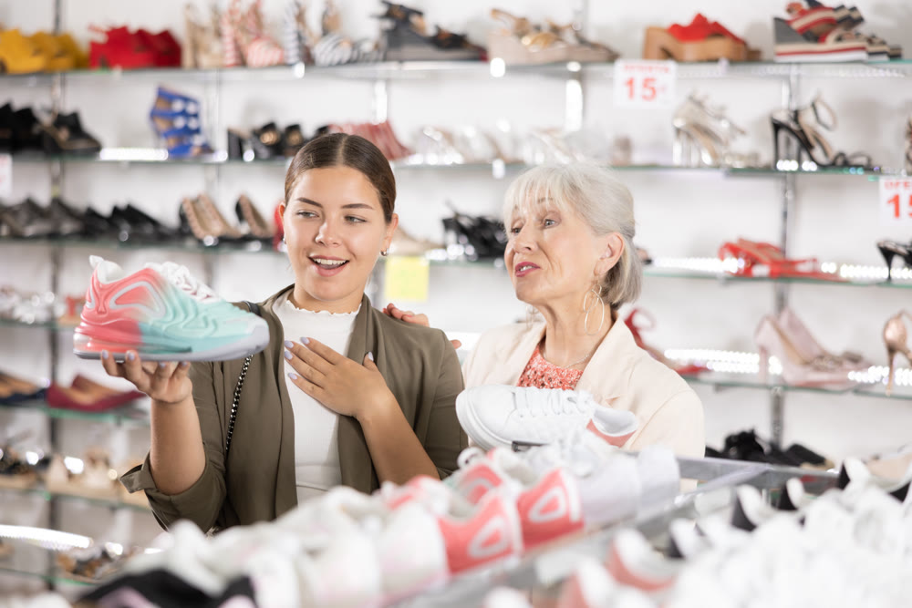 Young colleague shows elderly lady advantages of thick sole in modern sneakers