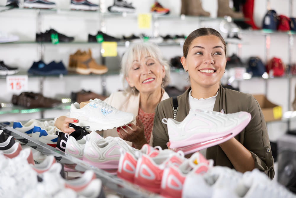 Elderly woman and young woman choosing sneakers in shoe store