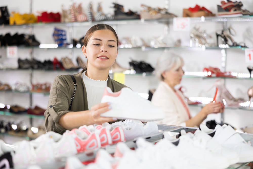 Young woman chooses sneakers in shoe store