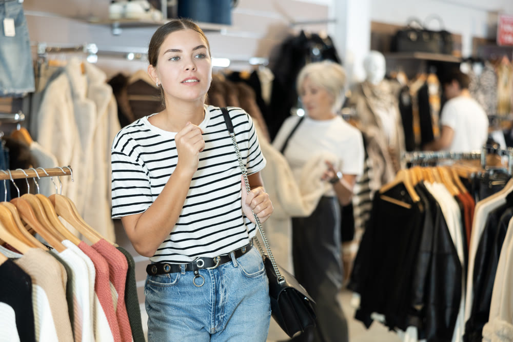 Young girl watching excitedly large stock of clothes in clothing store