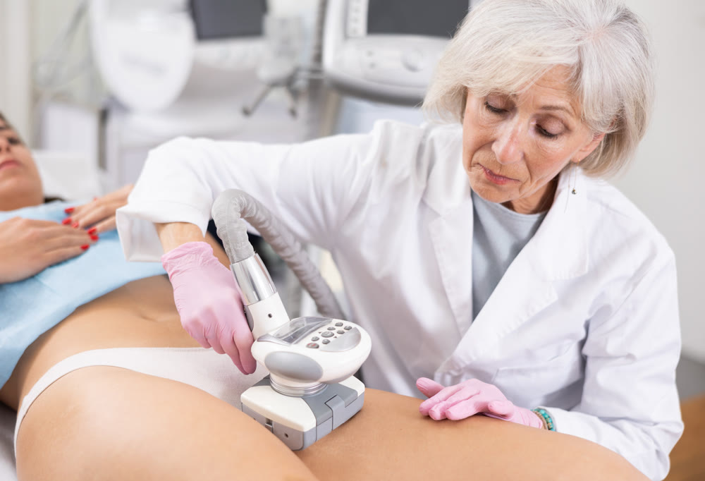 Old woman specialist doing LPG massage of hips of young woman