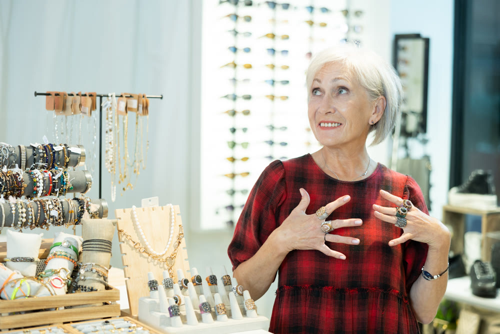 Delighted elderly lady admiring costume jewelry in trendy store