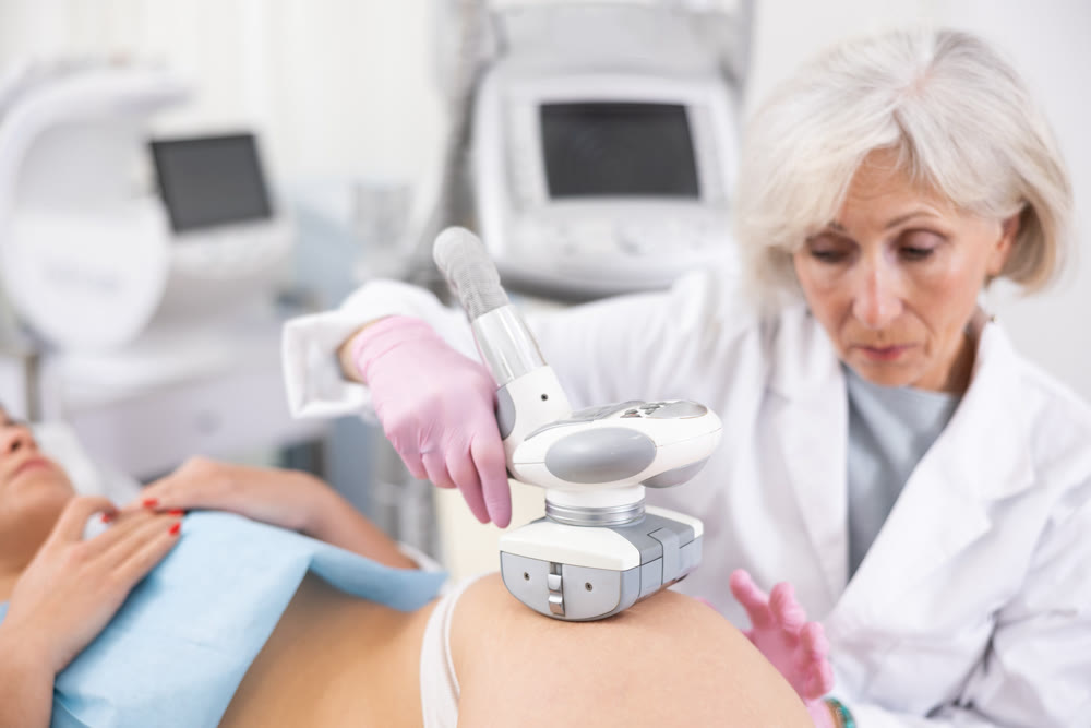 Old woman specialist doing LPG massage of hips of young woman